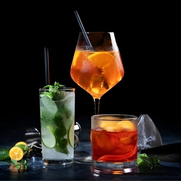 Three vibrant cocktails, a mojito, an Aperol Spritz, and an Old Fashioned, on a dark surface.